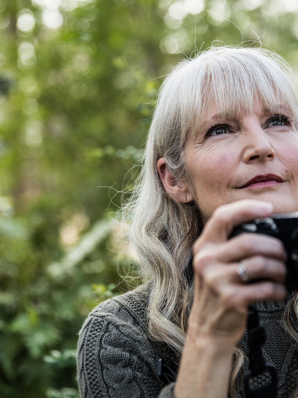Older woman taking a photo outdoors
