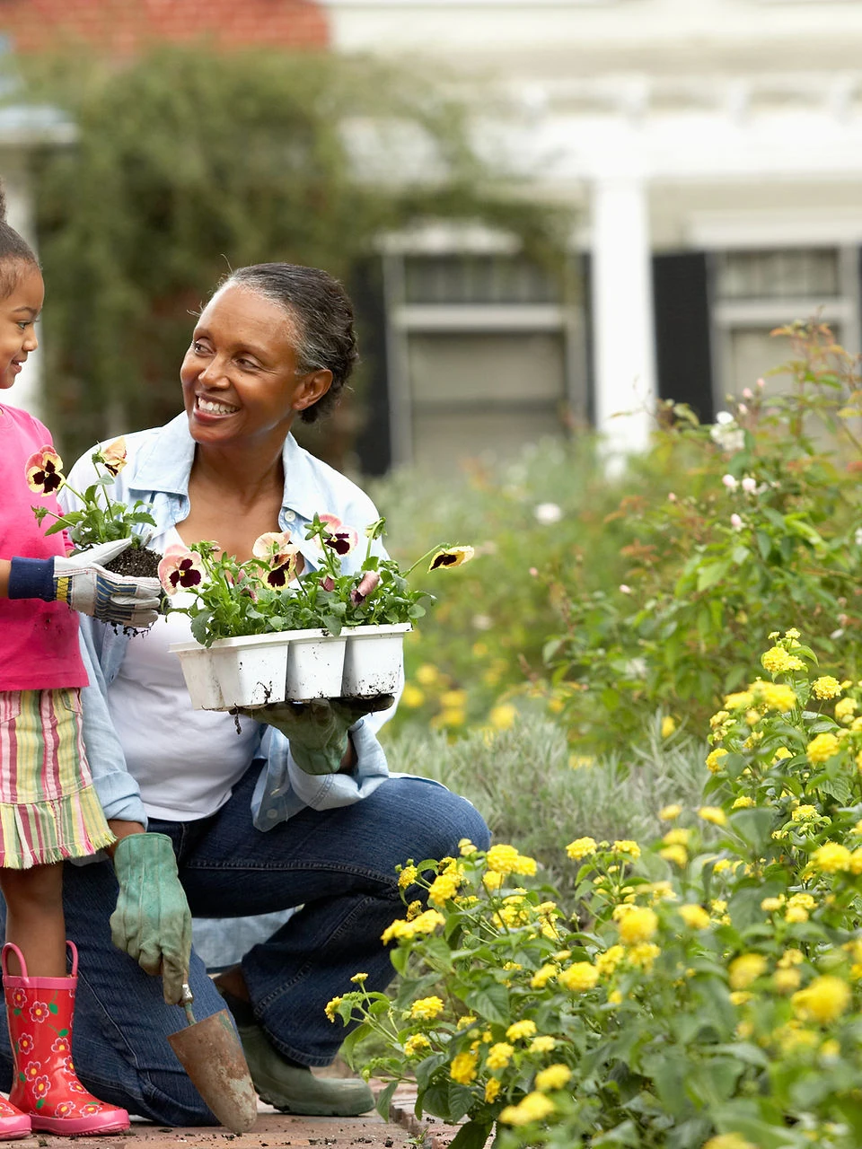 Woman and young girl planting flowers in a garden