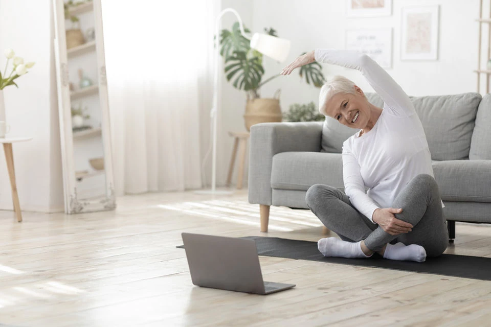 Older woman stretching at home during an online exercise class