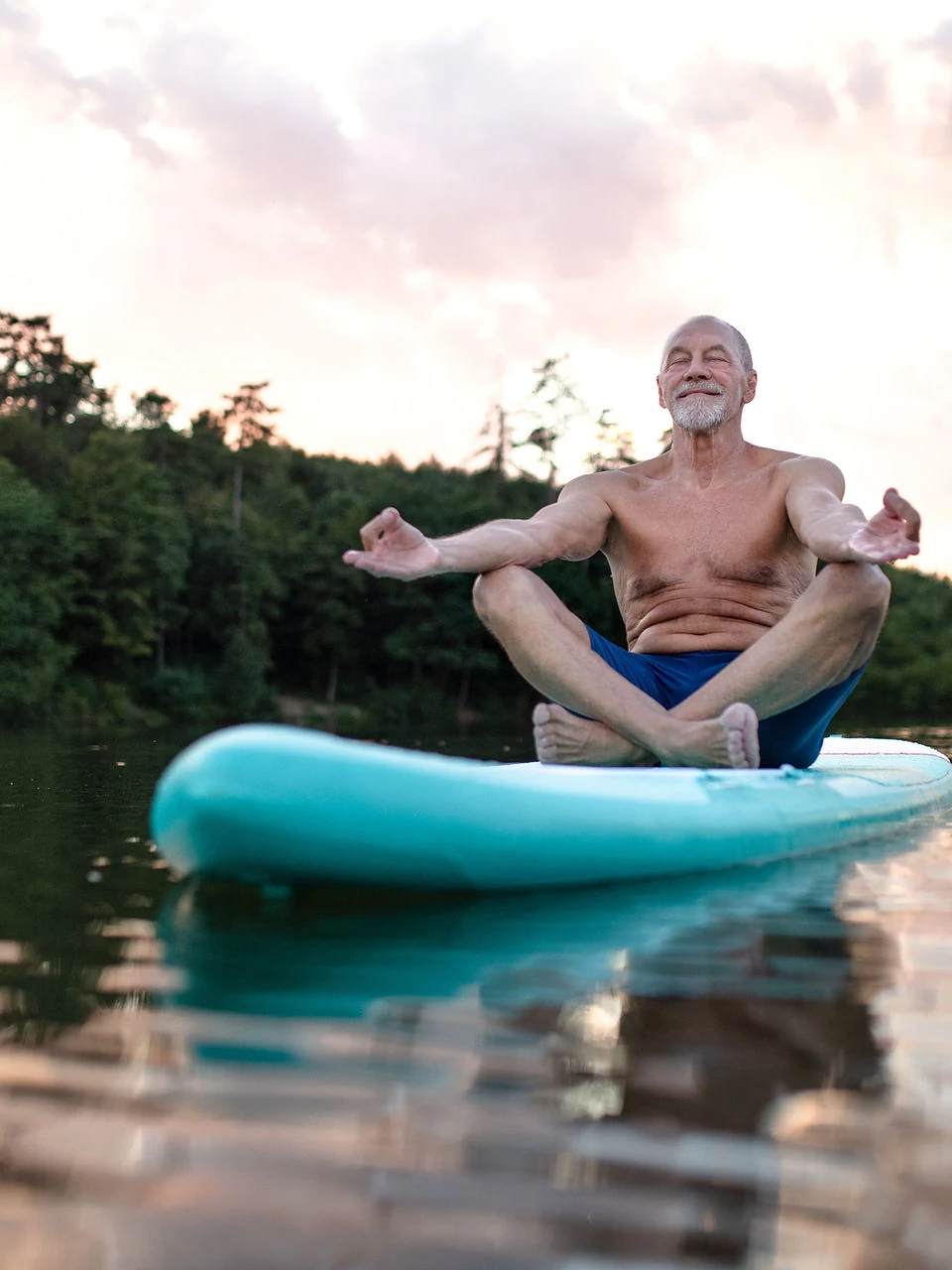 Man meditating on a paddleboard on a calm lake